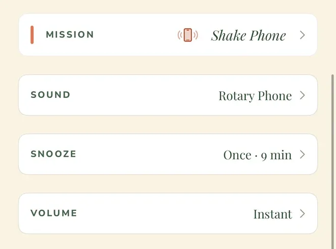 Four rows from one alarm’s settings, each with a chevron: “MISSION”, showing Shake Phone with a vibrating-phone icon and an orange marker at the left edge; “SOUND”, showing Rotary Phone; “SNOOZE”, showing “Once · 9 min”; and “VOLUME”, showing “Instant”.