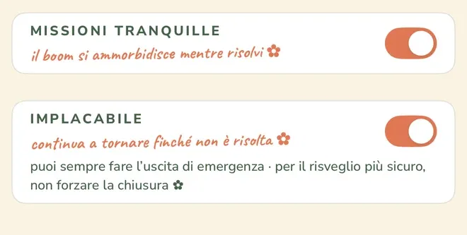 Due righe di impostazione nella schermata «Modifica sveglia» di Wake Boom in italiano, entrambe con l’interruttore attivo: la prima dice «MISSIONI TRANQUILLE» con la nota «il boom si ammorbidisce mentre risolvi ✿», la seconda dice «IMPLACABILE» con la nota «continua a tornare finché non è risolta ✿» e la riga piccola «puoi sempre fare l’uscita di emergenza · per il risveglio più sicuro, non forzare la chiusura ✿».